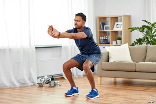 man performing a squat in his house