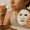 Person with acne applying spot treatment to chin while holding a sheet mask.
